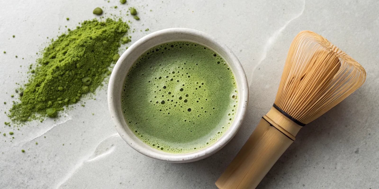A bowl of ceremonial matcha with a traditional bamboo whisk and powder.